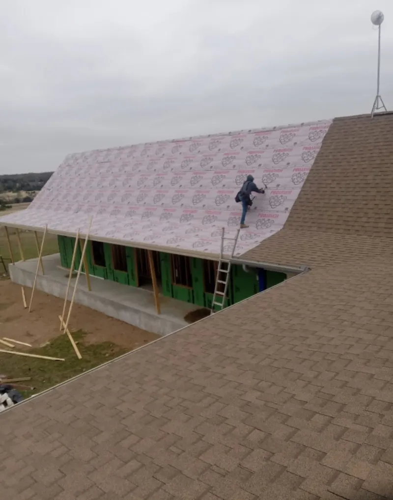 Worker preparing underlayment for a metal roof installation in Beachwood